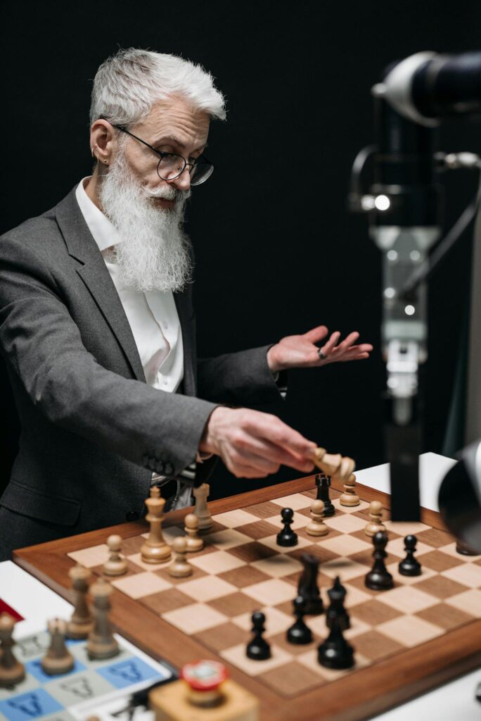 Crafting Captivating Headlines: Your awesome post title goes here Elderly man engages in a strategic chess game with a robotic arm, showcasing technology.